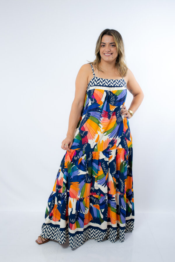 Este vestido longo com estampa tropical é perfeito para quem deseja um look leve, descontraído e cheio de cor. A estampa Vibrante com papagaios e elementos tropicais em tons intensos de laranja, azul, verde e amarelo traz uma energia contagiante para o seu visual.